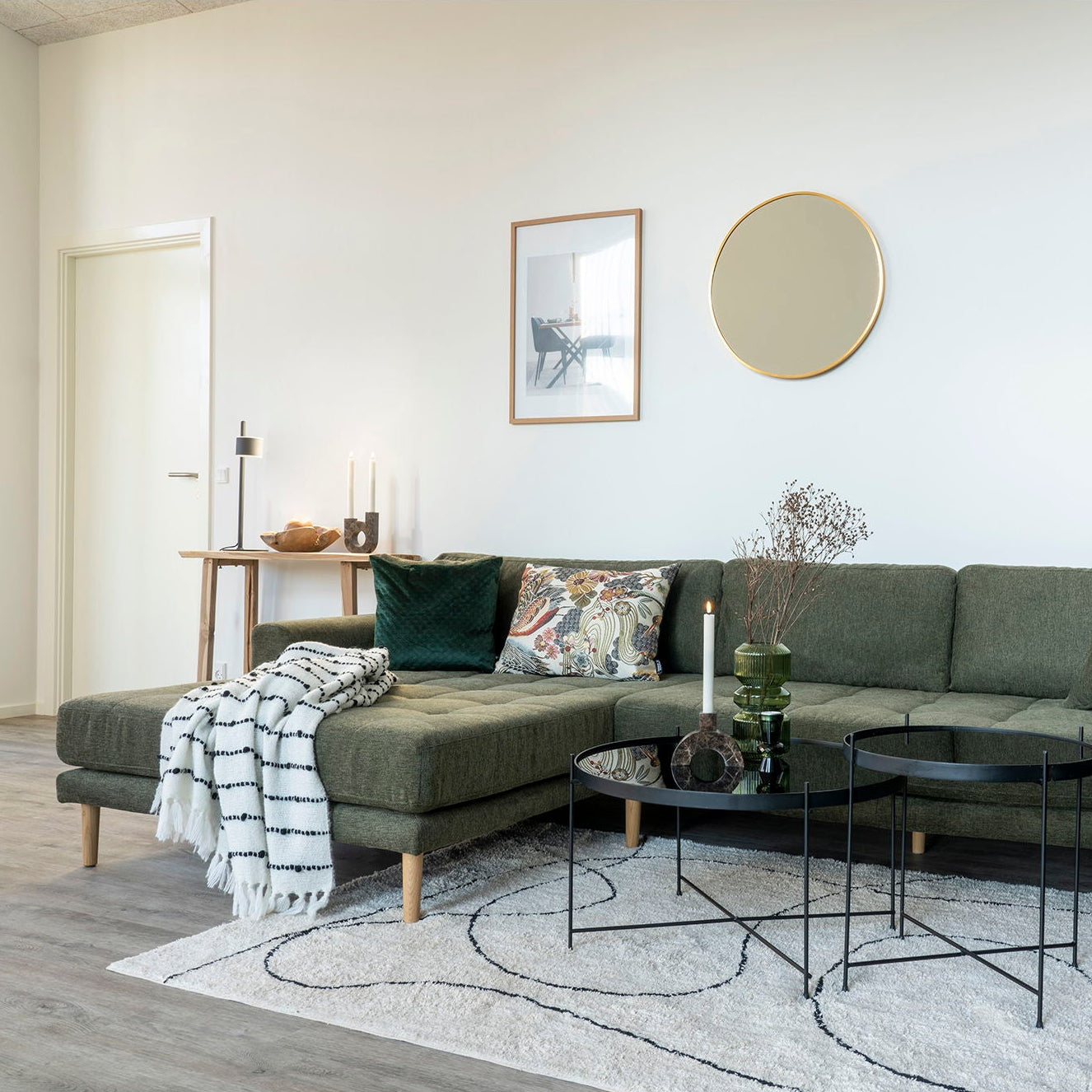 Modern living room with a green sectional sofa, coffee table, and decorative items.