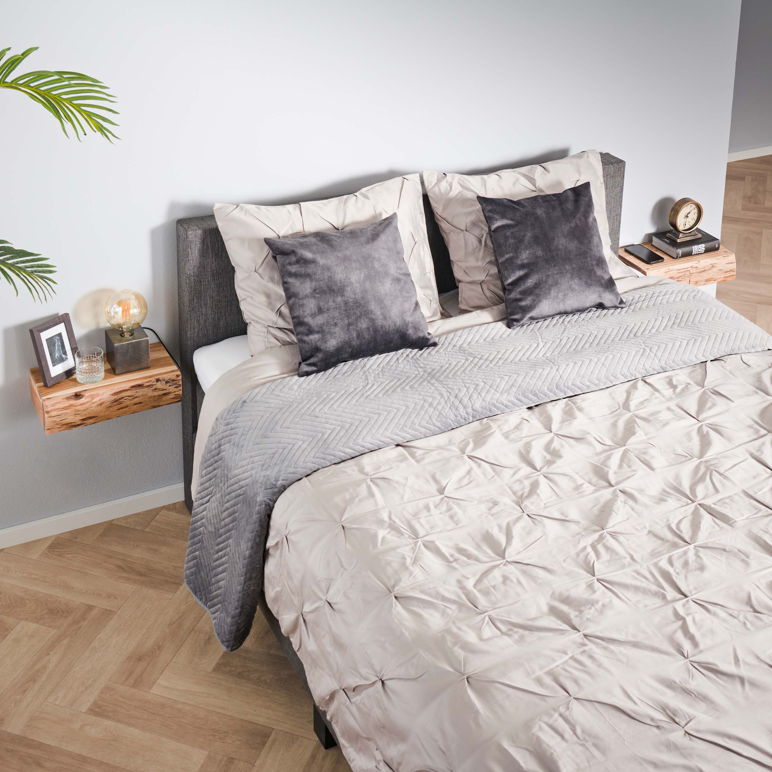 Neatly made bed with gray and beige bedding in a modern bedroom.